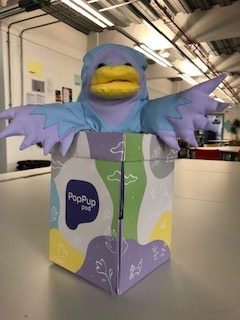 Bo the puppet (a light blue and light purple bird) sat in the PopPupPod box.